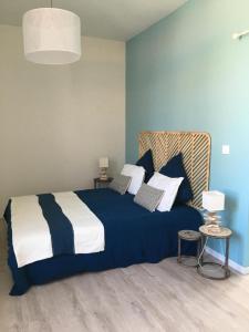 een slaapkamer met een blauw en wit bed en 2 tafels bij La possibilité d'une île in Boyardville