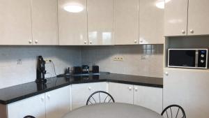 a kitchen with white cabinets and a microwave at Brelaarheide in Aan de Wolfsberg