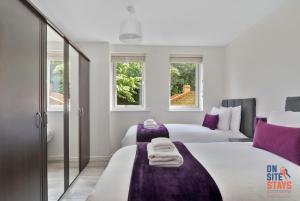 达特福德OnSiteStays - Contemporary 2 Bed Apt with Ensuite, 2 x Free Parking Spaces & a Balcony的有两张床和两扇窗户的卧室