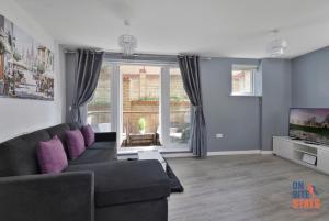 ein Wohnzimmer mit einem Sofa und einem TV in der Unterkunft OnSiteStays - Contemporary 2 Bed Apt with Ensuite, 2 x Free Parking Spaces & a Balcony in Dartford