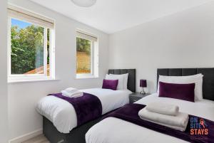 2 Betten in einem weißen Zimmer mit 2 Fenstern in der Unterkunft OnSiteStays - Contemporary 2 Bed Apt with Ensuite, 2 x Free Parking Spaces & a Balcony in Dartford