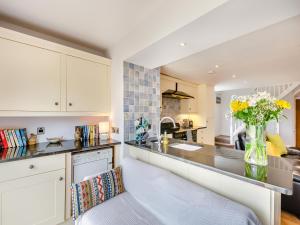 una cocina con armarios blancos y un jarrón de flores en Beacon - Uk44719, en Ravenscar