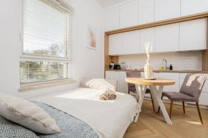 a bedroom with a bed and a table and a kitchen at Wiktoryn 21 Citysphere Premium Suite 2 in Warsaw