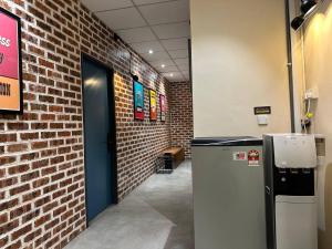 a hallway with a brick wall and a refrigerator at M-Stay Hostel in Chemor