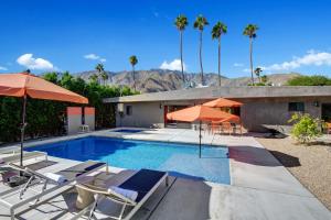 a swimming pool with chairs and umbrellas next to a house at Ultra Luxury Resort Like Compound Pool, Spa, Fire Pit- Close to Everything- 4BD/2.5BTH in Palm Springs