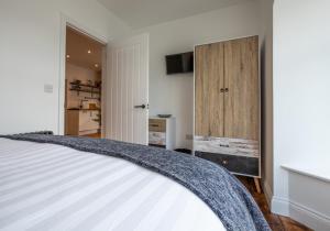een slaapkamer met een wit bed en een houten deur bij Ty Llwyd Apartments - Poppit in Saint Dogmaels