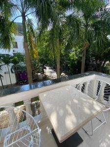 a white table and chairs on a balcony with palm trees at Paragon Hotel PMH in Ho Chi Minh City