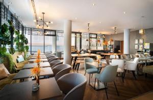 a restaurant with tables and chairs and a cafeteria at Leonardo Hotel Salzburg City Center in Salzburg