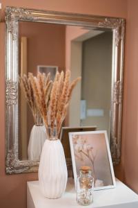 a white vase sitting on a table in front of a mirror at Imádnivaló társasházi lakás in Mosonmagyaróvár