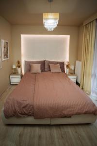 Un dormitorio con una cama grande y una lámpara de araña. en Imádnivaló társasházi lakás, en Mosonmagyaróvár