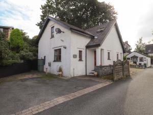 a white house with a black roof and a driveway at Cherry Tree Cottage in Windermere