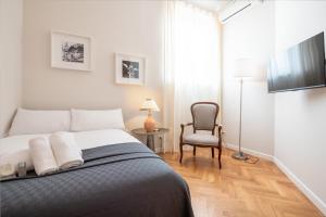 sypialnia z łóżkiem, krzesłem i telewizorem w obiekcie Top View Luxury apartment Piazza del Popolo w Rzymie