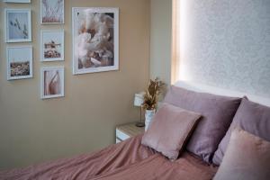 a bedroom with a bed with pink sheets and pictures on the wall at Imádnivaló társasházi lakás in Mosonmagyaróvár