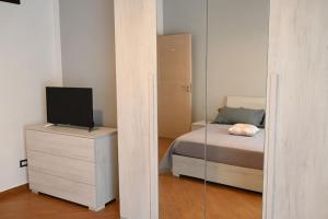 ein Schlafzimmer mit einem Bett mit einem Spiegel und einem TV in der Unterkunft White Oplonti House in Torre Annunziata