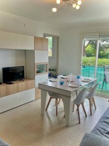 een eetkamer met een tafel en stoelen en een tv bij Appartement T2 lumineux, moderne avec parking et wifi - 4SABLE16 in Canet-en-Roussillon