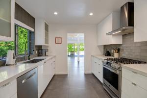 uma cozinha com armários brancos e um forno com placa de fogão em Trousdale Oasis- A tranquil and charming retreat, pool, spa, firepit, outdoor kitchen and more em Palm Springs