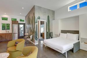 um quarto com uma cama branca e 2 cadeiras em Trousdale Oasis- A tranquil and charming retreat, pool, spa, firepit, outdoor kitchen and more em Palm Springs