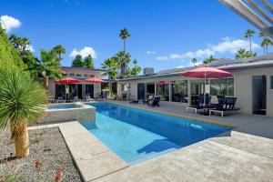 uma piscina com cadeiras e guarda-sóis ao lado de uma casa em Trousdale Oasis- A tranquil and charming retreat, pool, spa, firepit, outdoor kitchen and more em Palm Springs