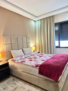 a bedroom with a large bed with a purple blanket at App à côté du parc et corniche in Mohammedia