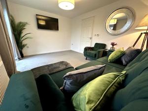 a living room with two green couches and a mirror at Middlebeck House by Blue Skies Stays in Middlesbrough