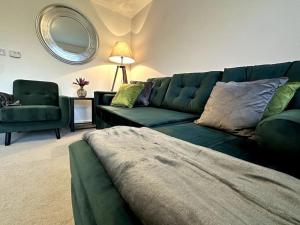 a living room with a green couch and a mirror at Middlebeck House by Blue Skies Stays in Middlesbrough