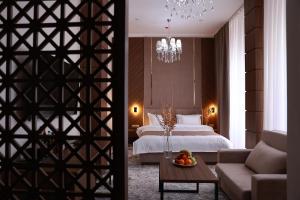 1 dormitorio con 1 cama y sala de estar con mesa en DAMIR HOTEL, en Nukus