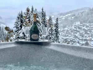 レ・ジェにあるChalet Luxury 5-Les Gets-Luxe-confort-jacuzzi-à 400 m des pistes et vue montagne Mont Chéryの- スイミングプールの上に座るワイン1本