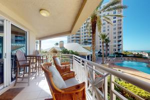 a balcony with chairs and a table and a pool at Mandalay Beach Club San Marco 403 in Clearwater Beach