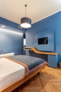 una camera da letto con una parete blu, un letto e una TV di Le Texture Premium Rooms Duomo-Cordusio a Milano