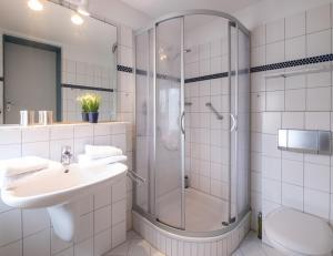 baño blanco con ducha y lavamanos en Haus Regina Maris, Wohnung 7 en Norderney