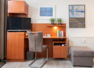a room with a desk with a television and a chair at Haus Regina Maris, Wohnung 7 in Norderney