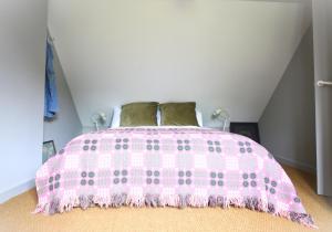 a pink bed with a pink comforter in a bedroom at Ty Newydd - a scandi inspired cottage in Moylgrove