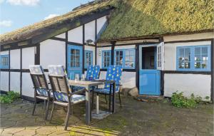 una mesa y sillas frente a una casa con techo de paja en Amazing Home In Horslunde With Kitchen en Horslunde