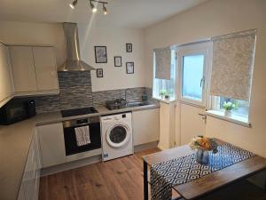 a kitchen with a washer and dryer in it at Hereford House - Welcome Short Stays in Derby