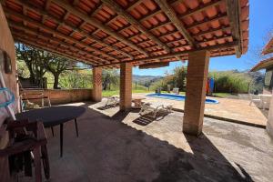 a covered patio with a table and a pool at Estância Village de Cunha in Cunha