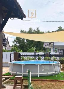 una piscina en un patio con una sombrilla grande en Blumeen Villa 2 en Kuala Terengganu