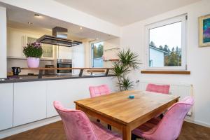 a kitchen and dining room with a wooden table and pink chairs at Deine Traumwohnung in Bad Saulgau