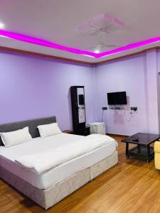 1 dormitorio con 1 cama grande con luces moradas en Vrundavan home stay and Village resort, en Kevadia