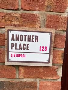 a sign on the side of a brick wall at Another Place in Formby