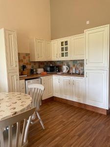 a kitchen with white cabinets and a table with chairs at Another Place in Formby