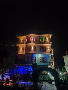 ein Gebäude mit farbenfroher Beleuchtung in der Nacht in der Unterkunft Majestic Mountain Bhaiji Guest House in Kasol