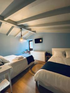 1 dormitorio con 2 camas, escritorio y TV en Casa Aturuxo, en Belesar