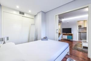 1 dormitorio blanco con 1 cama blanca y TV en apartamento con garaje en ensanche de vallecas, en Madrid