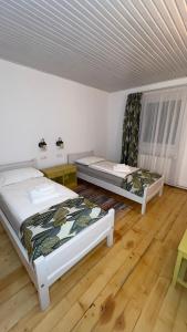 two beds in a room with wooden floors at Casa de Oaspeți Vulcan in Braşov