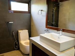 a bathroom with a sink and a toilet and a mirror at Coastal Hideaway in Midigama