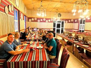 un grupo de personas sentadas en una mesa larga en un restaurante en Dream Desert Camp 