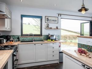 Una cocina con gabinetes blancos y una ventana grande. en Stargazing Retreat, en Merton
