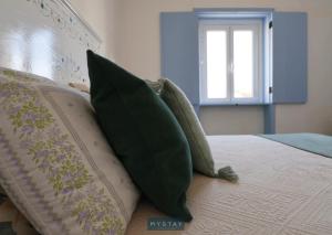 un letto con cuscini verdi e finestra di MyStay - Cantinho do Açor a Vale de Açor Altre 21 foto
