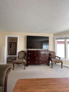 a living room with a tv and two chairs and a dresser at Waterfront cozy cottage. in Port Perry