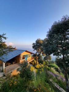 a house on a hill with trees and flowers at Kot Kailash Kumaon in Almora